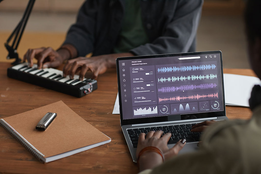 Close up of unrecognizable African-American musician using laptop with sound editing software